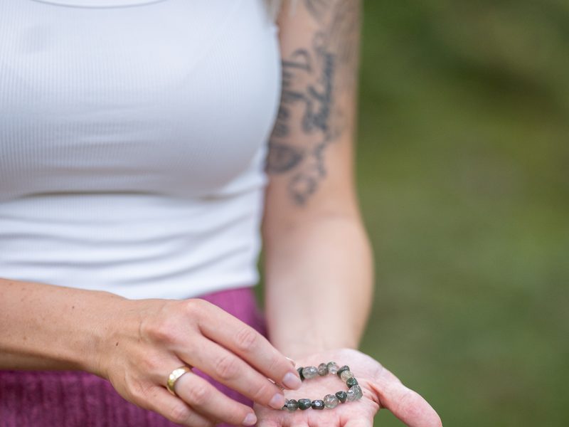 Hände, die ein Armband aus Heilsteinen halten